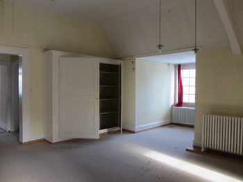 Das alte Dachgeschoss mit großem Einbauschrank und altem Teppich.